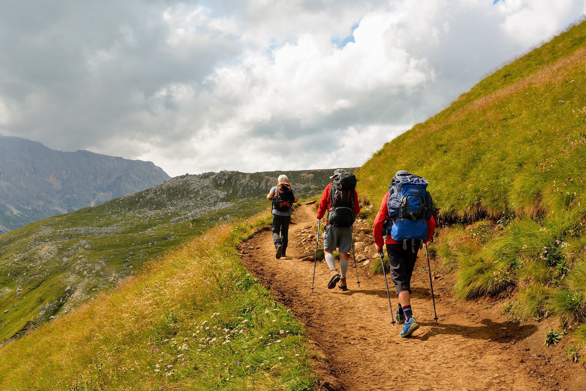 3 guys doing trekking along side of a hill with trekking gear